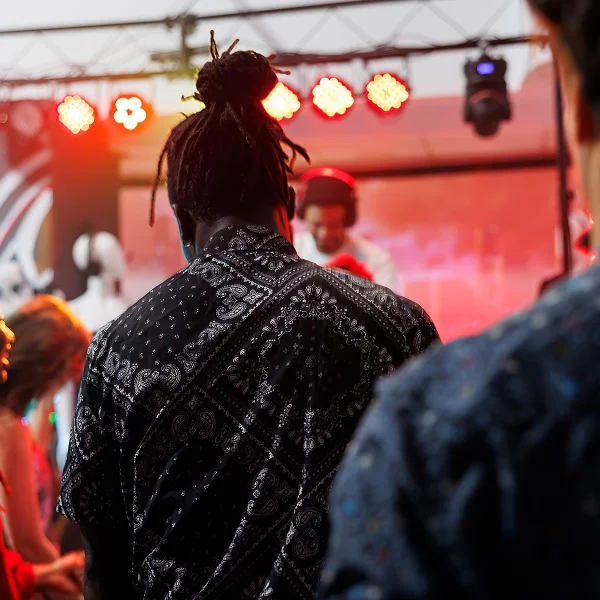 Un homme aux dreadlocks se tient devant une foule, captivant l'attention des spectateurs.